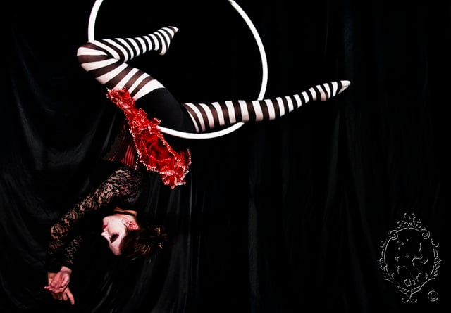 Acròbata fent acrobàcia amb un cercle aeri penjat.