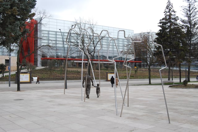 Grup escultòric "Camí de l'Evolució" de Cast Solano amb el MEH de fons, representació artística de l'evolució humana.